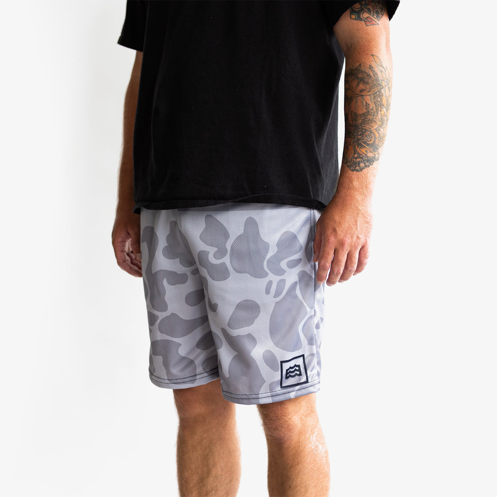 lower half of man wearing split white and gray camouflaged shorts