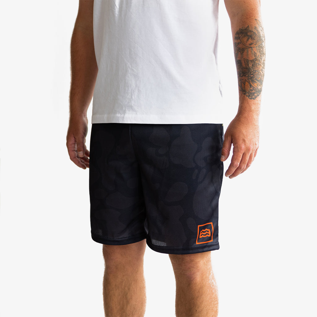 lower half of man wearing split green and navy camouflaged shorts