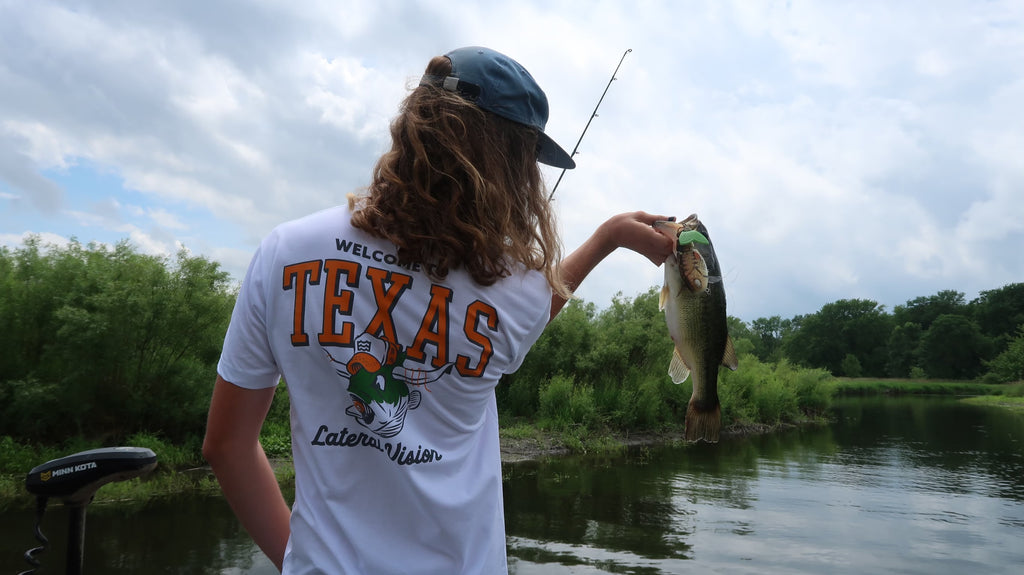 back of man holding up fish wearing new welcome to texas t-shirt